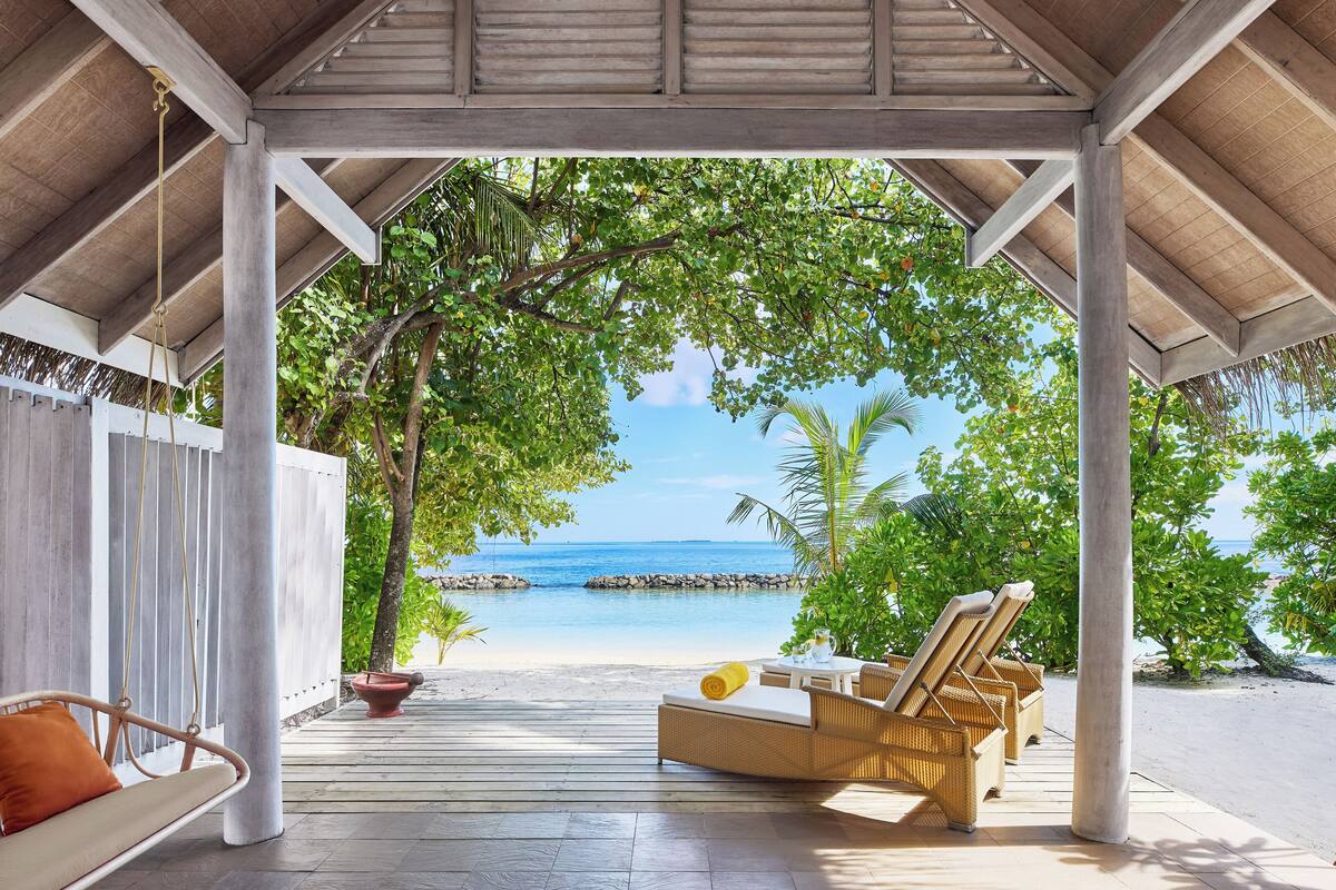 A covered outdoor seating area with a view of the beach and ocean.