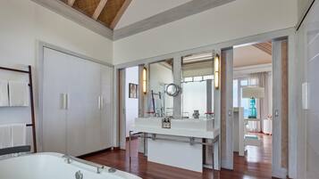 A modern bathroom with a large bathtub, a vanity with a mirror, and a view of the adjacent room.