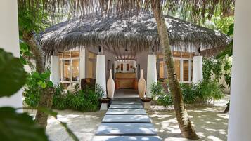 A resort with a thatched roof structure, a central seating area, and a pathway leading to the entrance.