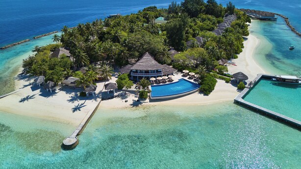 An aerial view of a tropical island resort with a large swimming pool, palm trees, and a beach. - NH Maldives Kuda Rah Resort (Kuda Rah)