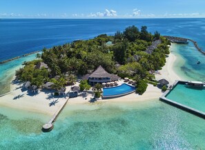 An aerial view of a tropical island resort with a large swimming pool, palm trees, and a beach. - NH Maldives Kuda Rah Resort (Kuda Rah)