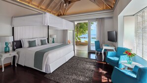 A modern hotel room with a large bed, a ceiling fan, a TV, and a view of the sea. - NH Maldives Kuda Rah Resort (Kuda Rah)