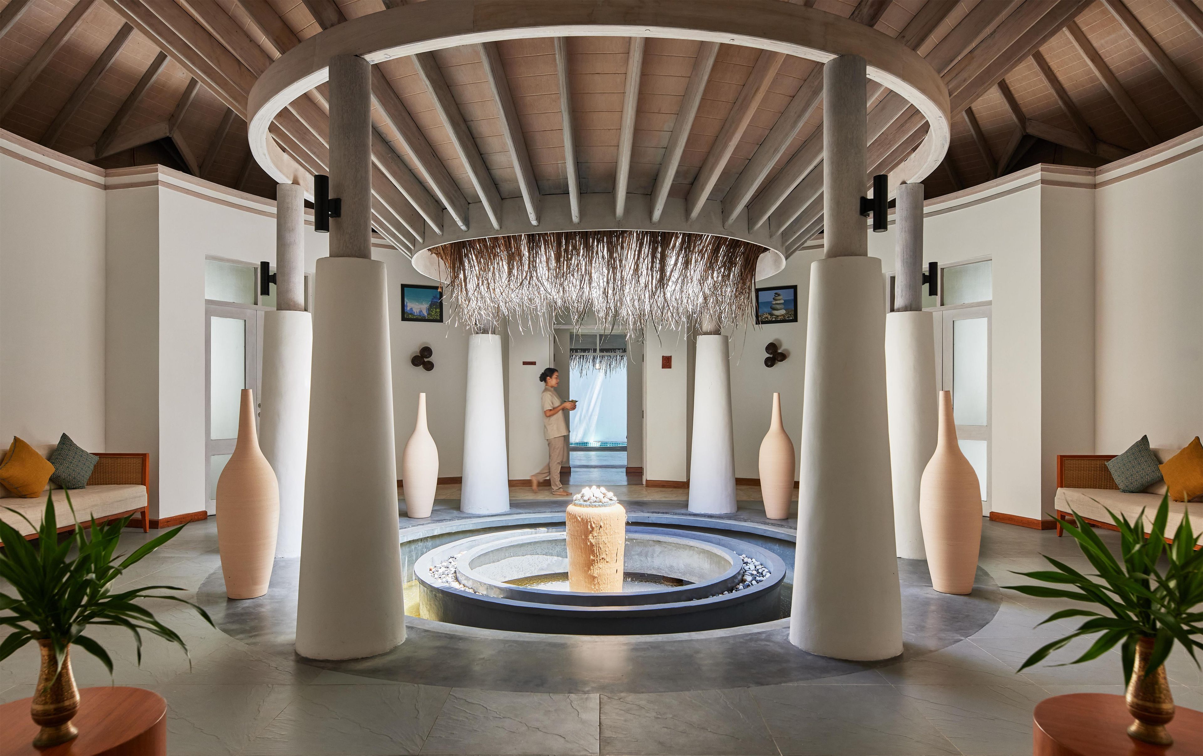 A spacious lobby with a central fountain, high ceilings with wooden beams, and modern furnishings.