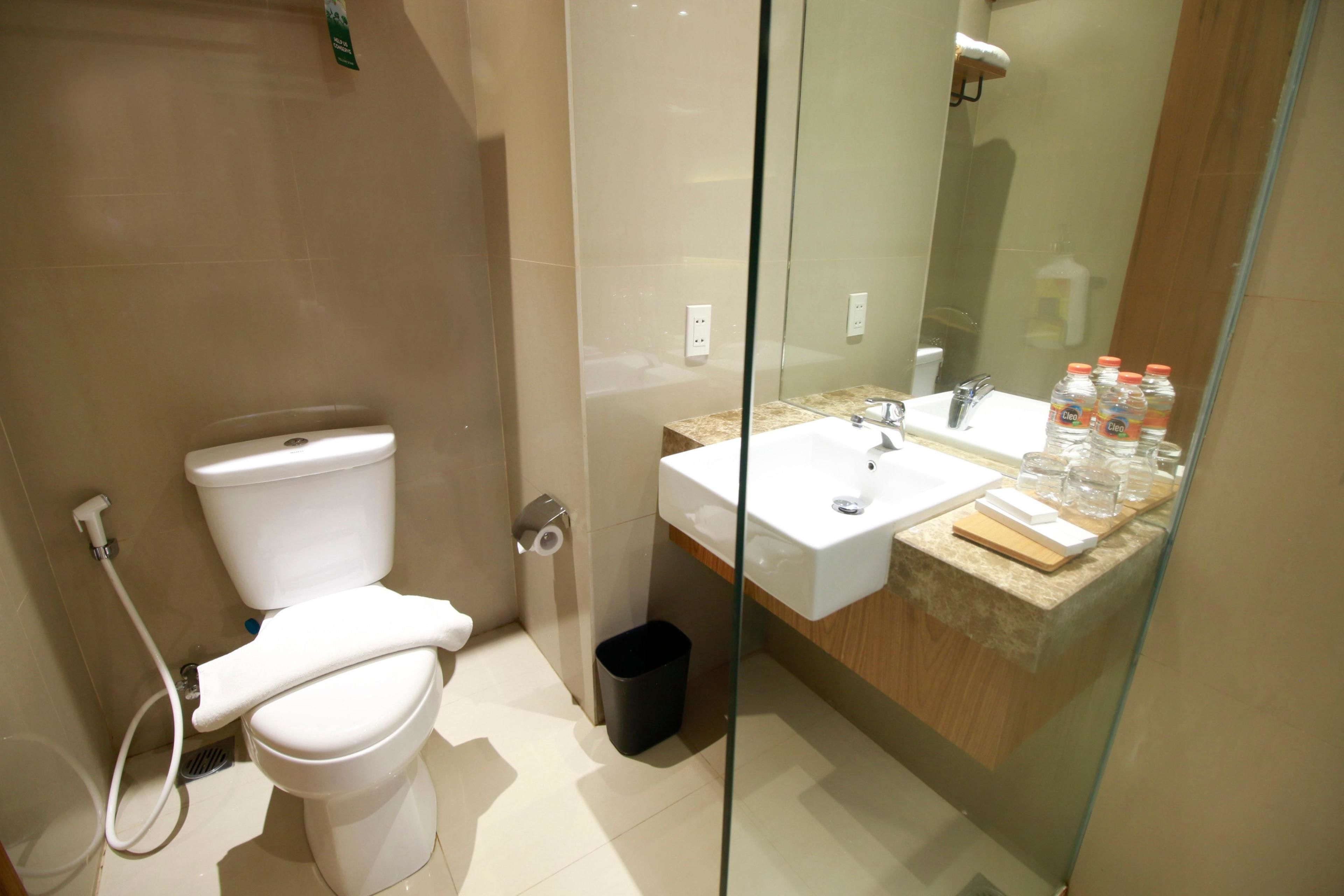 Een moderne badkamer met toilet, wastafel en een douchecabine met glazen wanden.