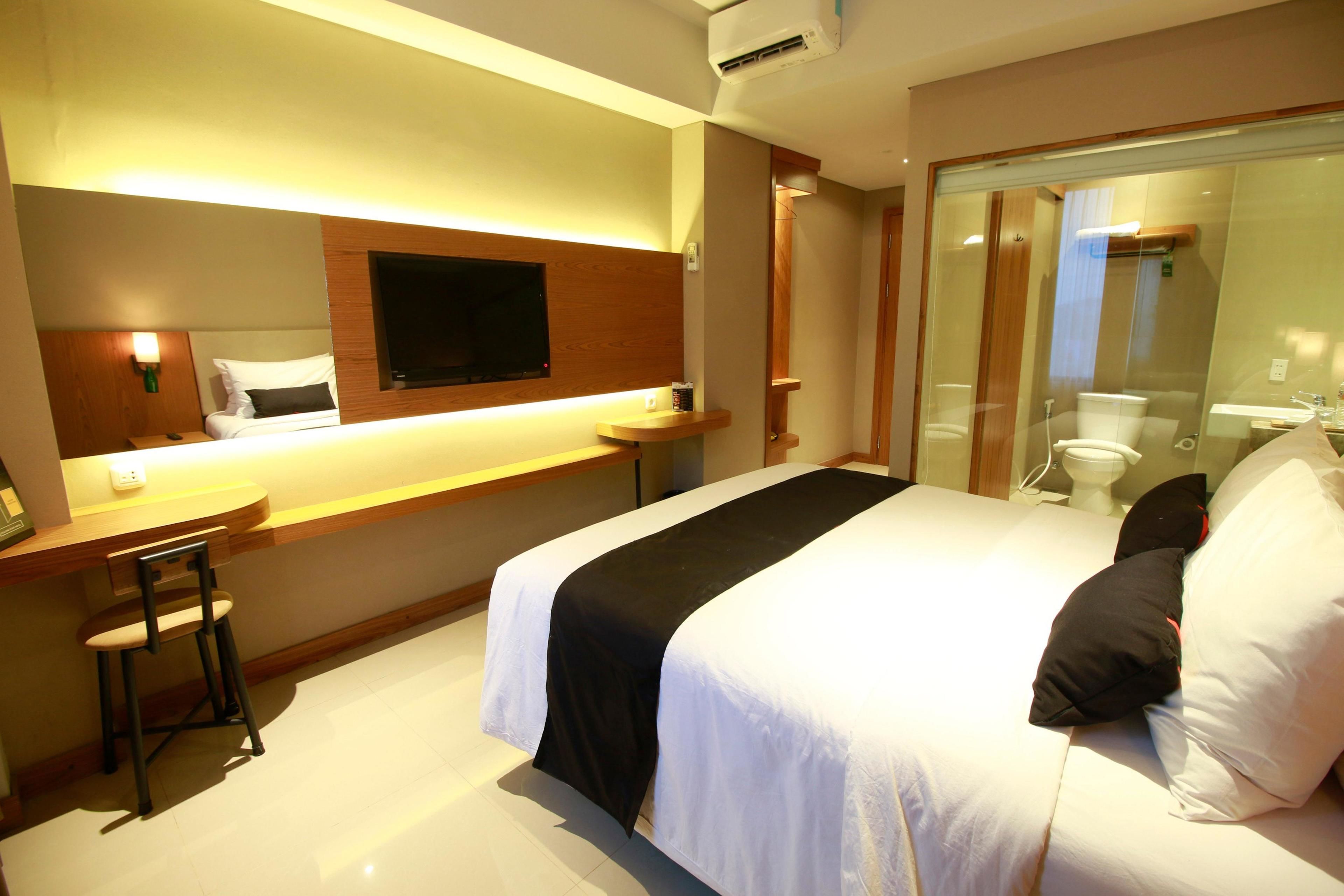 A hotel room with a bed, a desk, a chair, a TV, and a bathroom.