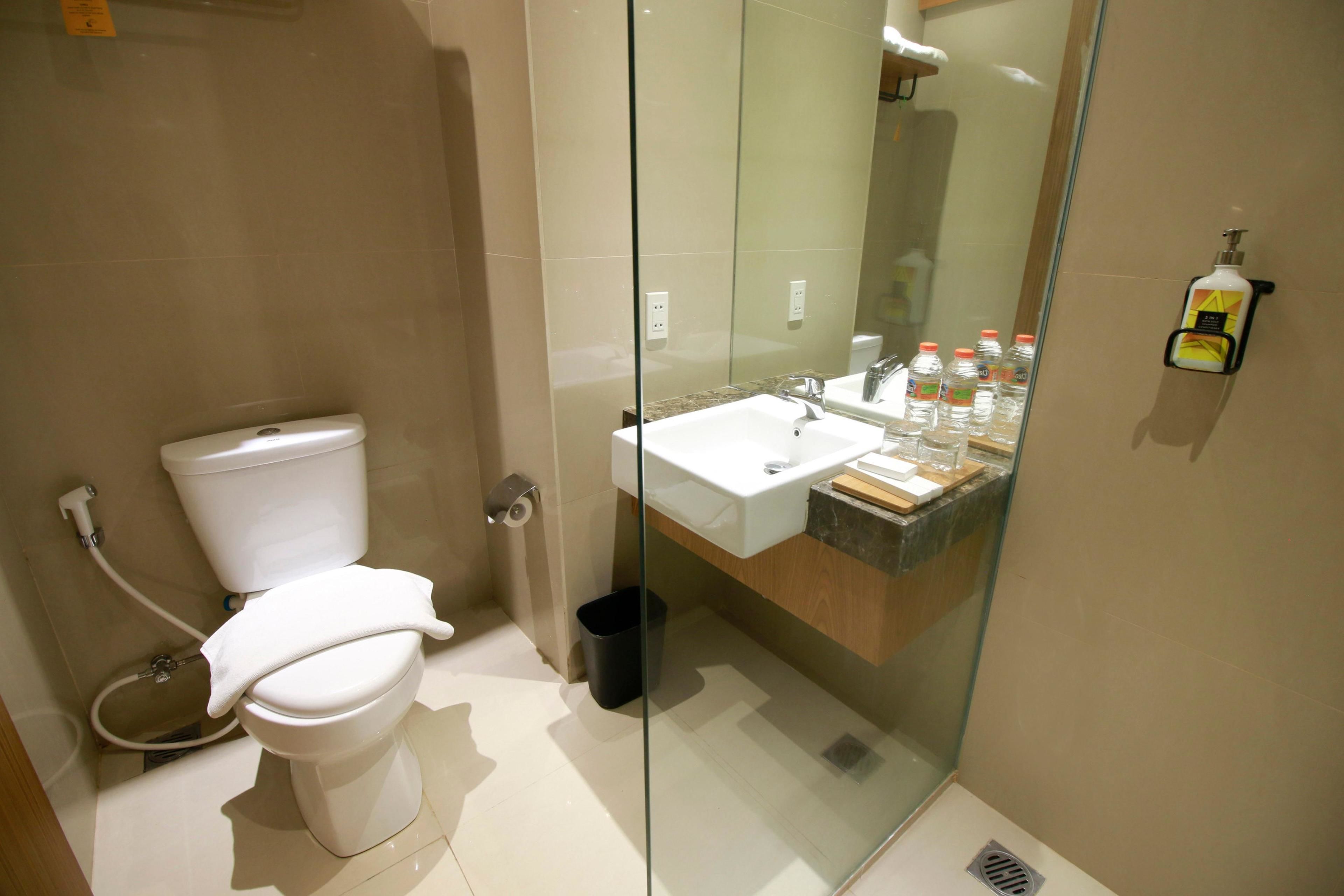 A modern bathroom with a toilet, sink, and glass shower enclosure.