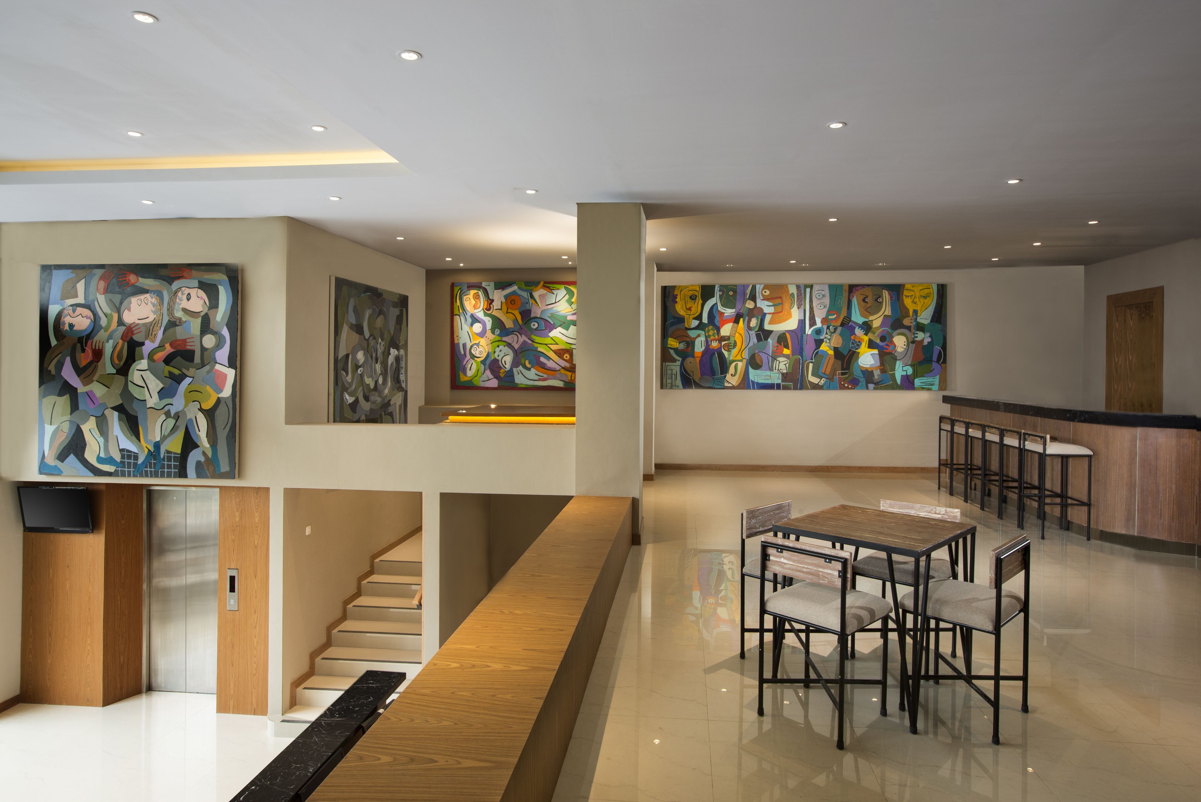 A modern lobby with abstract art, a staircase, and a dining area with tables and chairs.