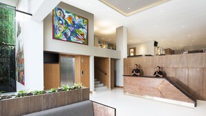 Un vestíbulo moderno con una recepción, una escalera y un cuadro abstracto de gran tamaño.