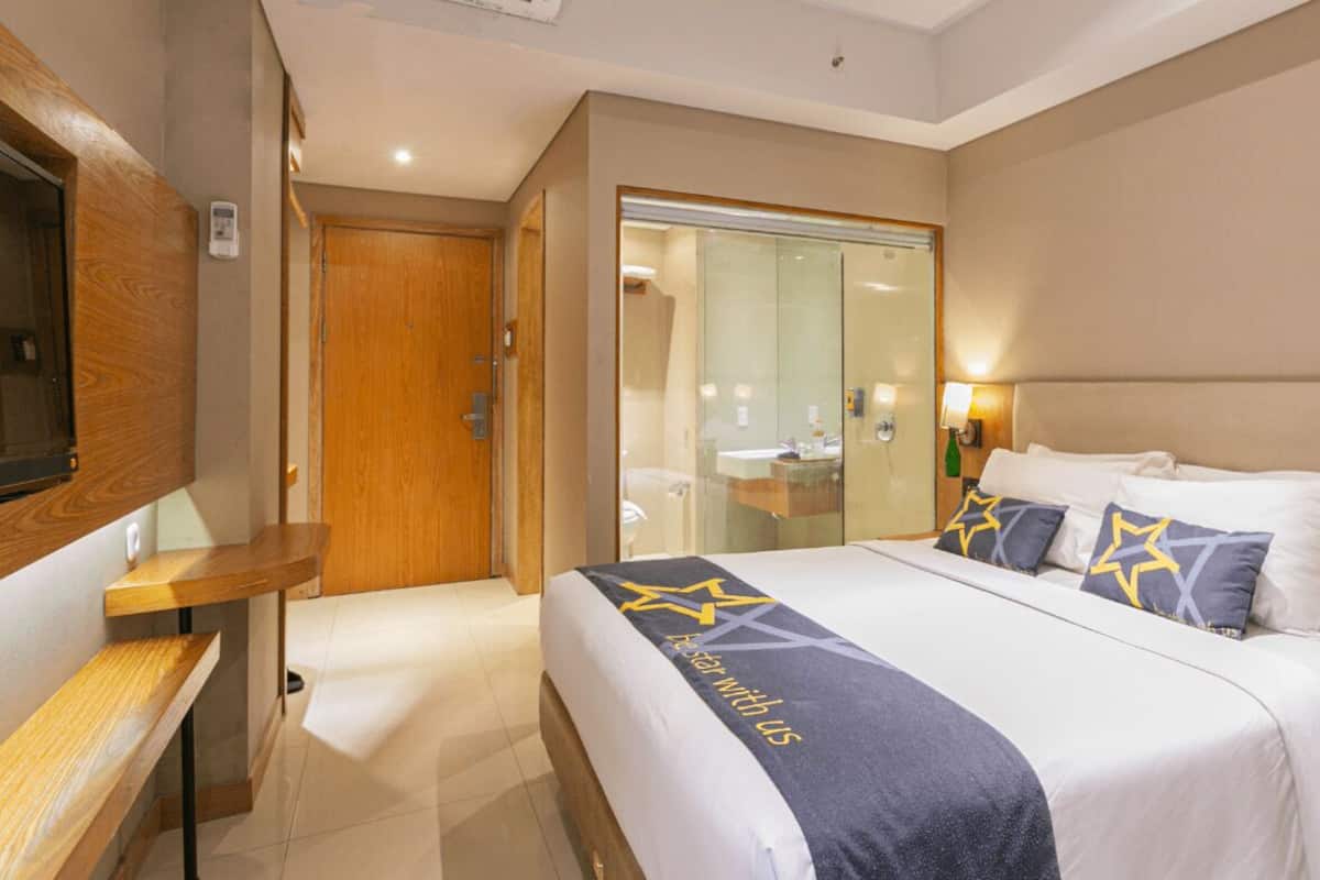 Ein Hotelzimmer mit einem Bett, einem Nachttisch und einem an der Wand montierten Fernseher.