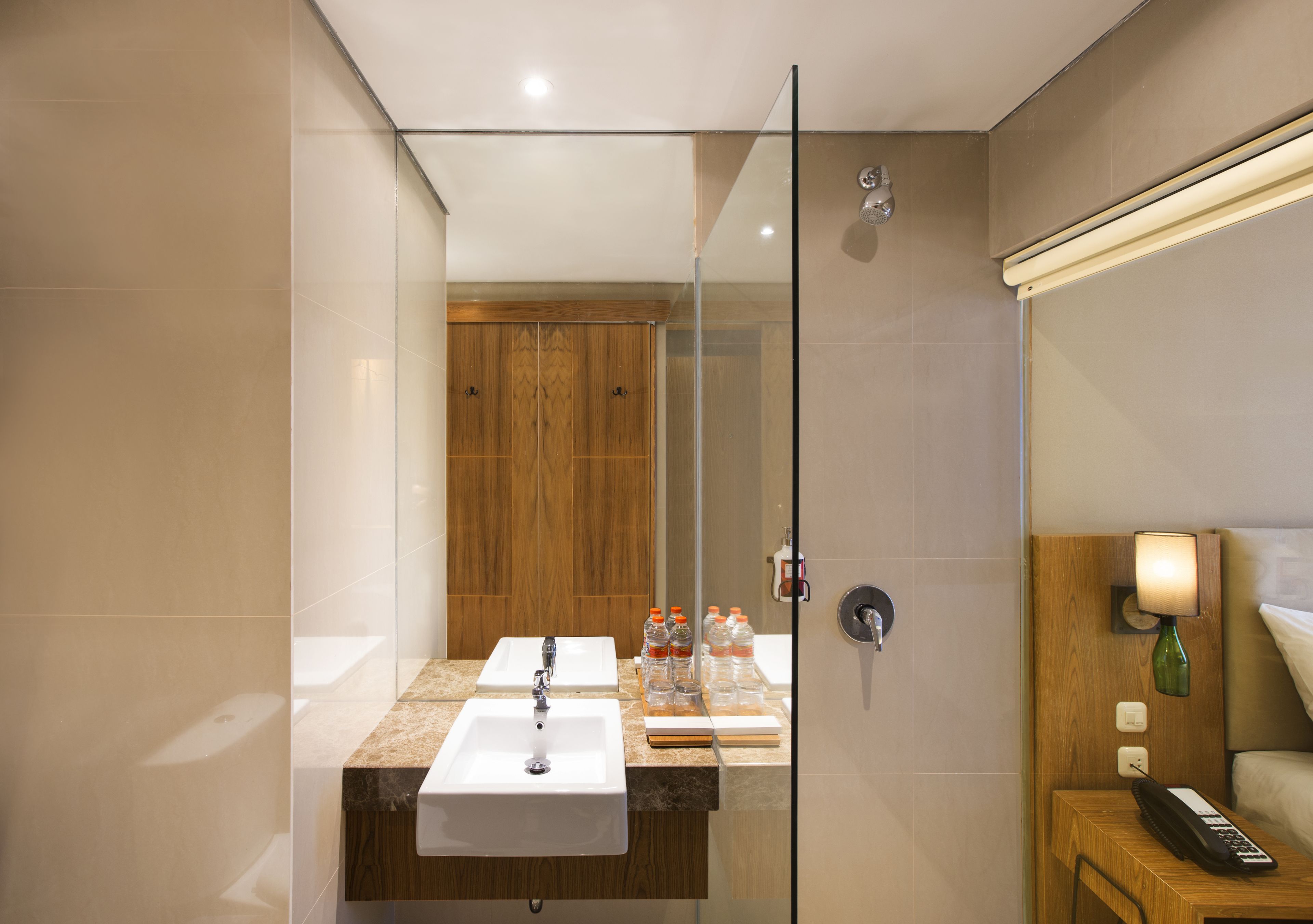 A modern bathroom with a glass shower enclosure, a sink with a marble countertop, and a wooden vanity.