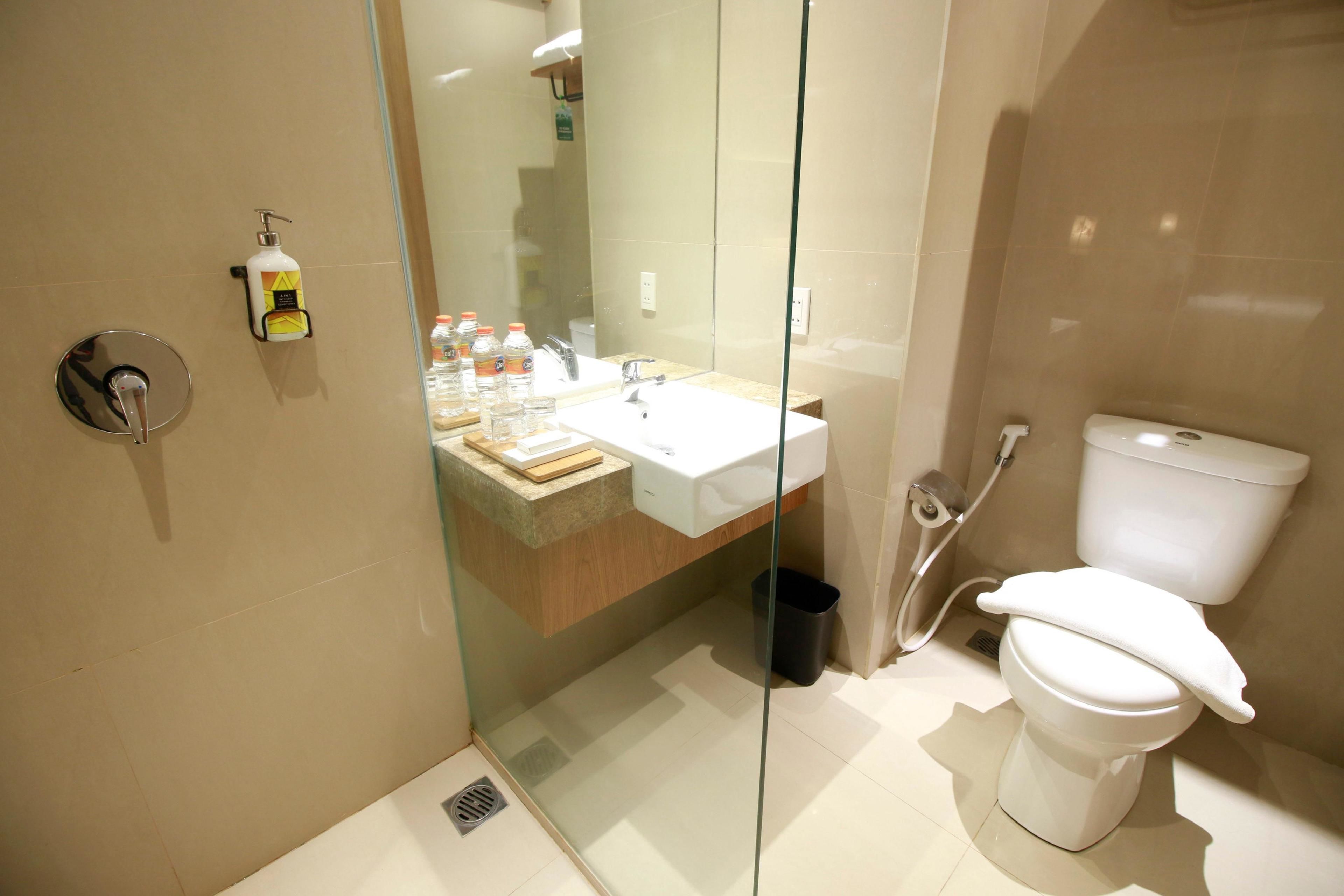 Et moderne badeværelse med en brusekabine med glaslåge, en hvid vask og et toilet.
