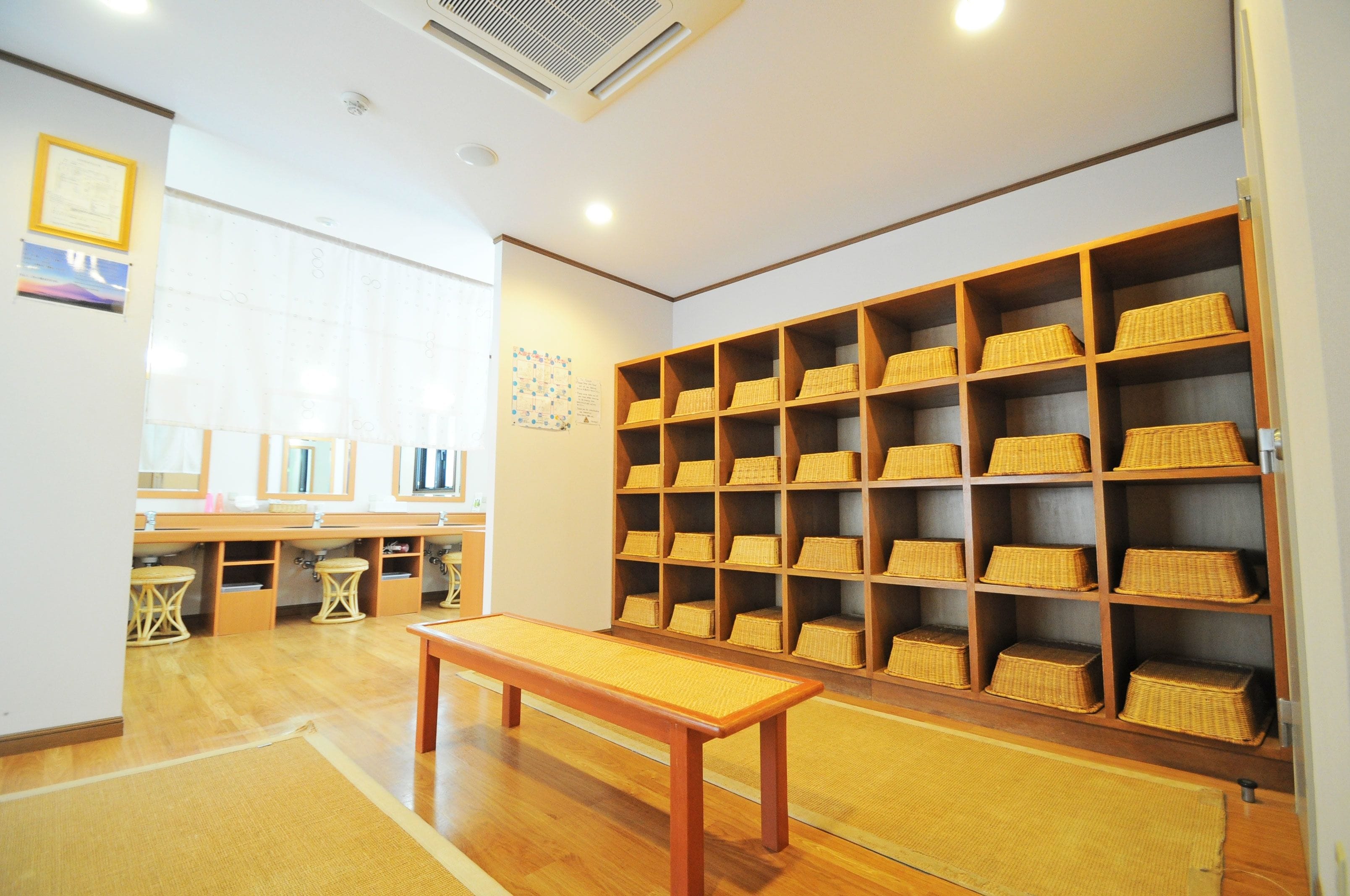 A room with a wooden bench, shelves with baskets, and a large window.