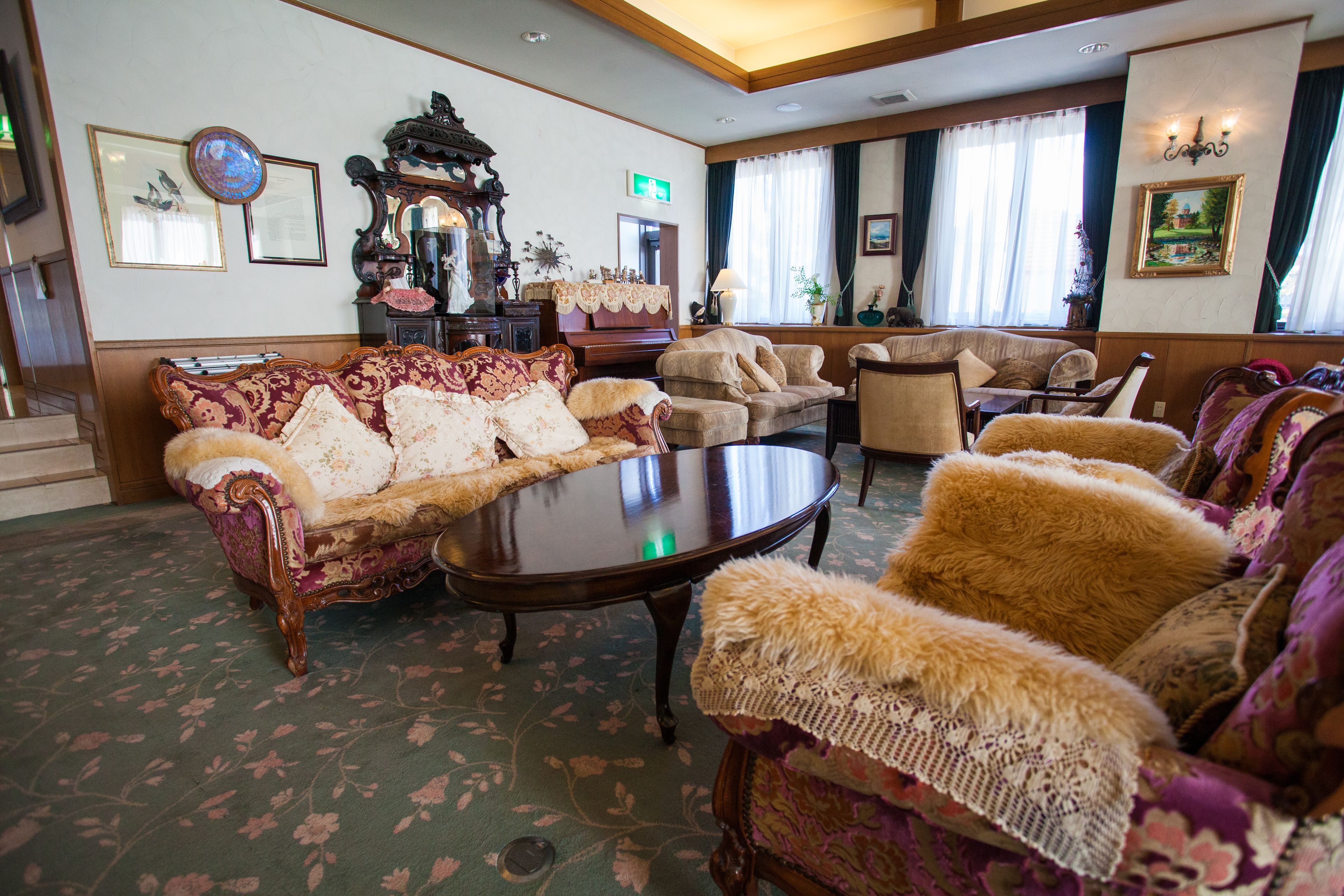 A spacious lobby with ornate furniture, a piano, and a large mirror.