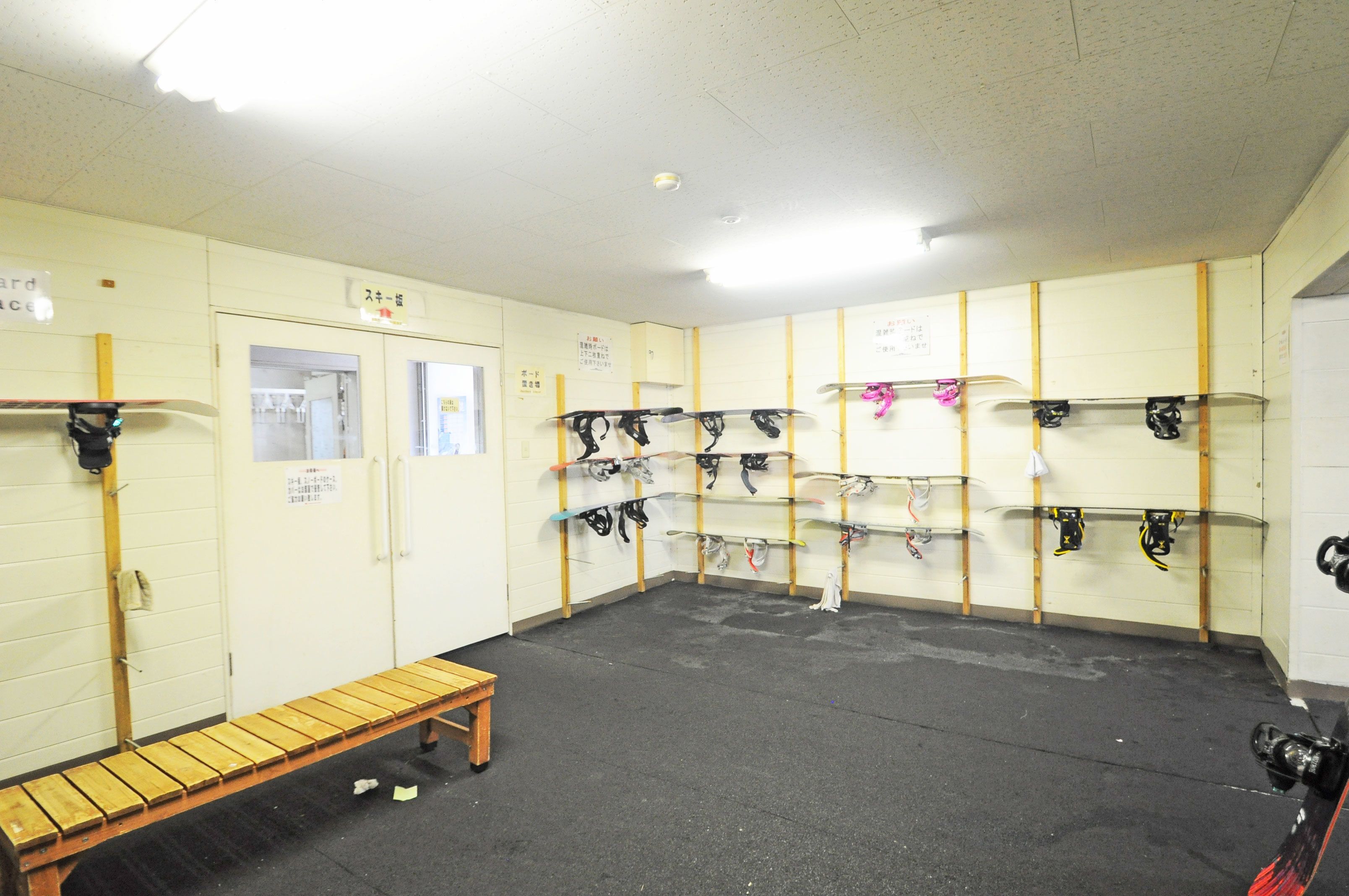 A locker room with multiple lockers, a bench, and a shower area.
