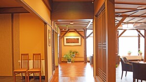 Un pasillo con suelo de madera, mostrador de recepción y sillas.