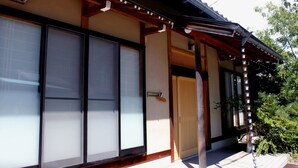 A traditional Japanese building with sliding doors, a wooden porch, and a tiled roof.