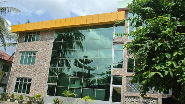 A modern building with a stone facade, large glass windows, and a yellow roof. - Yaewaddy Motel (Yangon)