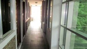 A corridor with a tiled floor, large windows on one side, and a door on the other. - Yaewaddy Motel (Yangon)