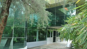 A modern building with large glass windows, a concrete floor, and potted plants. - Yaewaddy Motel (Yangon)