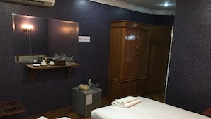 A hotel room with two beds, a wooden wardrobe, a small table with toiletries, and a mirror with lights. - Yaewaddy Motel (Yangon)