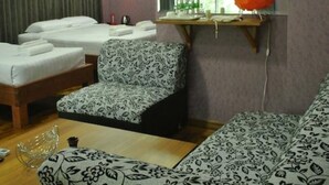 A hotel room with two beds, a patterned armchair, a sofa, a small table, and a mirror. - Yaewaddy Motel (Yangon)