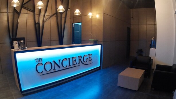 A reception desk with 'The Concierge' sign, modern pendant lighting, and a minimalist interior design. - The Concierge at Wind Residences Tagaytay (Tagaytay)