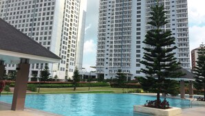 A swimming pool with a modern building in the background. - The Concierge at Wind Residences Tagaytay (Tagaytay)