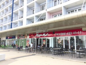 A Pizza Hut restaurant with outdoor seating, a DO Express store, and a multi-story building in the background. - The Concierge at Wind Residences Tagaytay (Tagaytay)