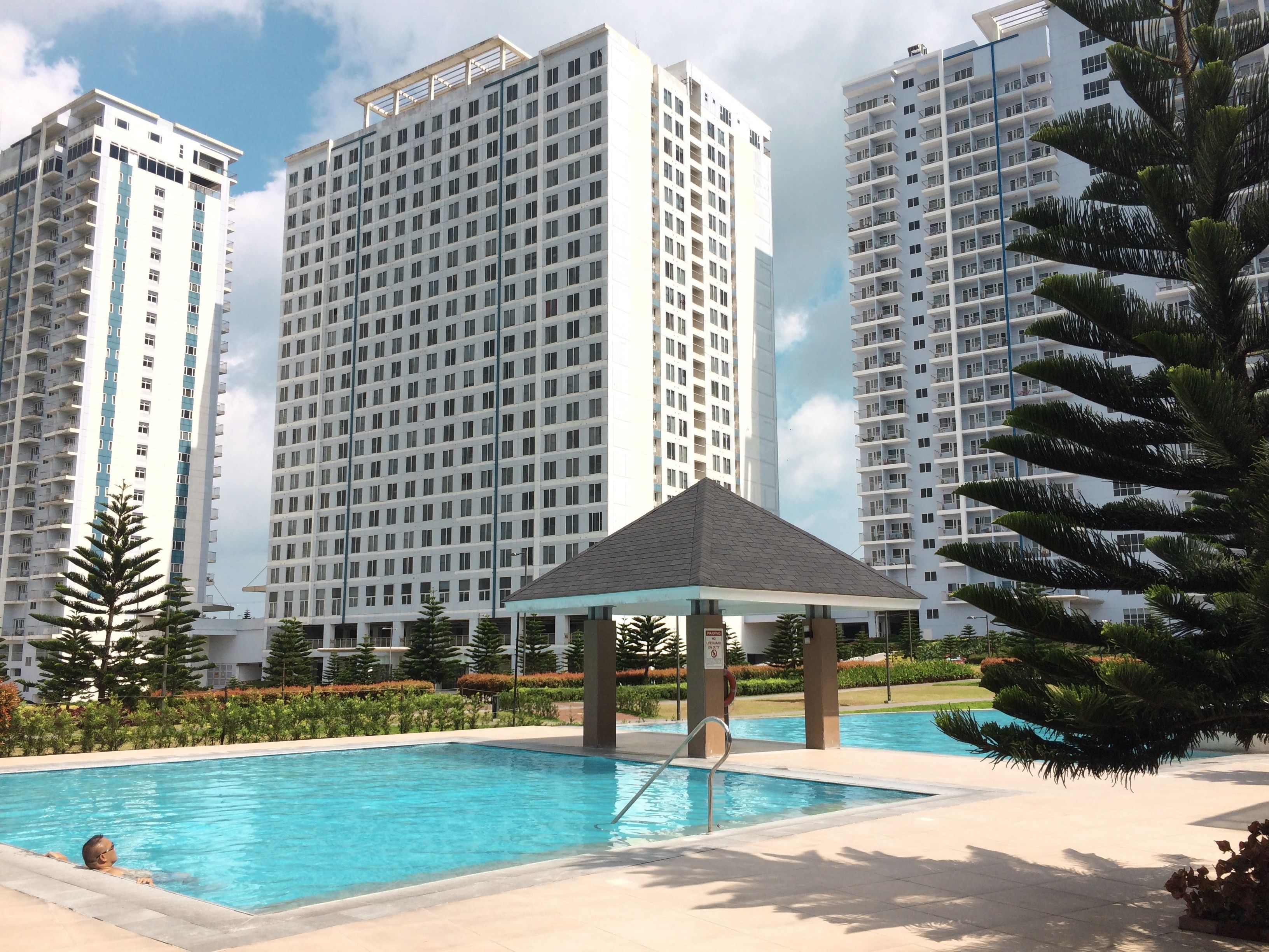 A modern residential building complex with a swimming pool and a gazebo.