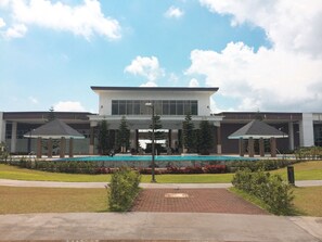 A modern building with a swimming pool, covered walkways, and a landscaped garden. - The Concierge at Wind Residences Tagaytay (Tagaytay)