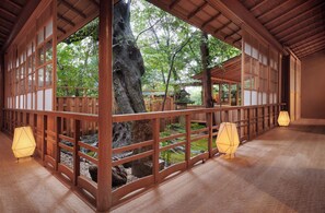 A traditional Japanese-style room with tatami flooring, wooden sliding doors, and a view of a garden. - Araya Totoan (Kaga)