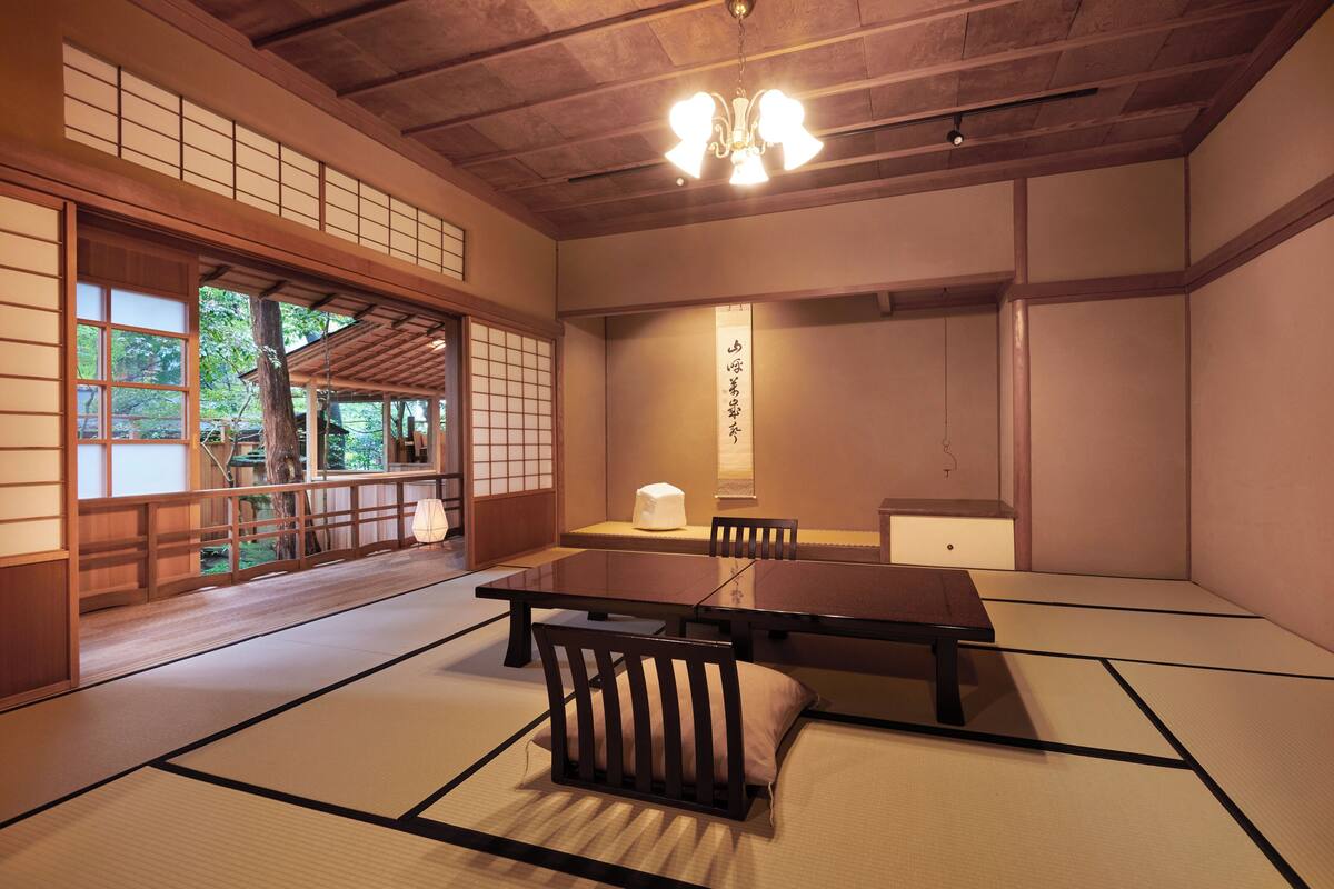 A traditional Japanese room with tatami flooring, a low table, and a hanging lantern.