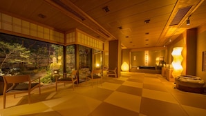 Une pièce de style japonais traditionnel, avec un sol recouvert de tatamis, des portes coulissantes et une vue sur un jardin.