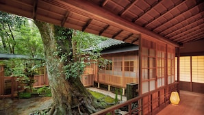 Un bâtiment traditionnel en bois, avec un grand arbre dans la cour.
