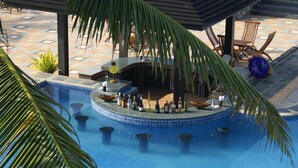 Área de piscina com bar e assentos sob uma estrutura coberta.