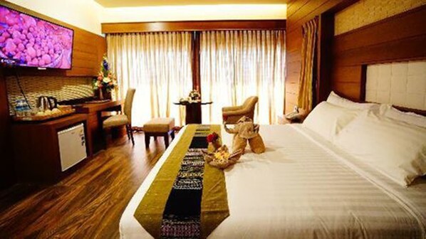 A hotel room with a bed, a desk with a computer, a chair, and a television. - Sunny Paradise Resort (Ngwe Saung)