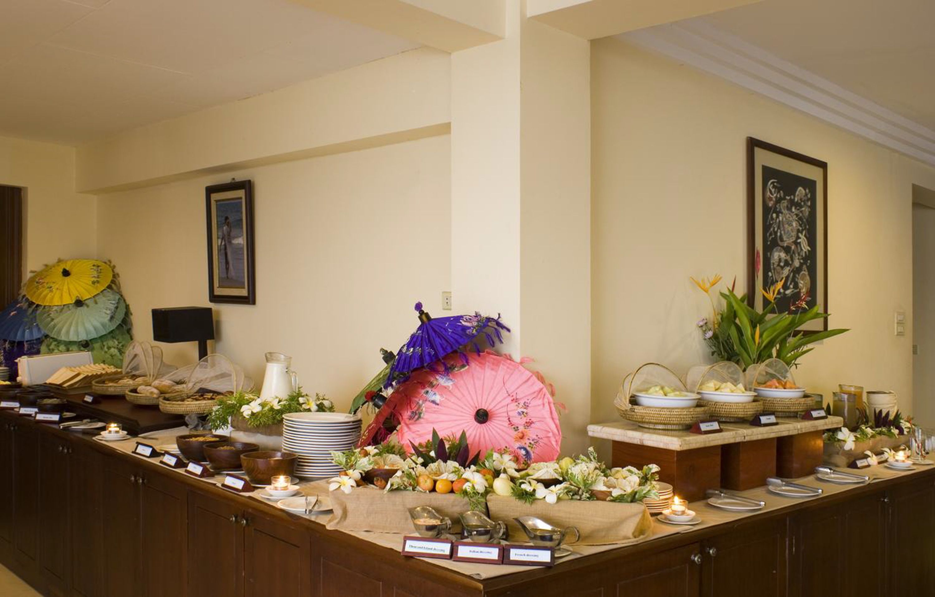 A buffet setup with various food items, a pink umbrella centerpiece, and decorative elements like flowers and candles.