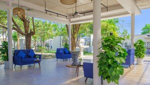 A covered outdoor seating area with blue sofas and potted plants.