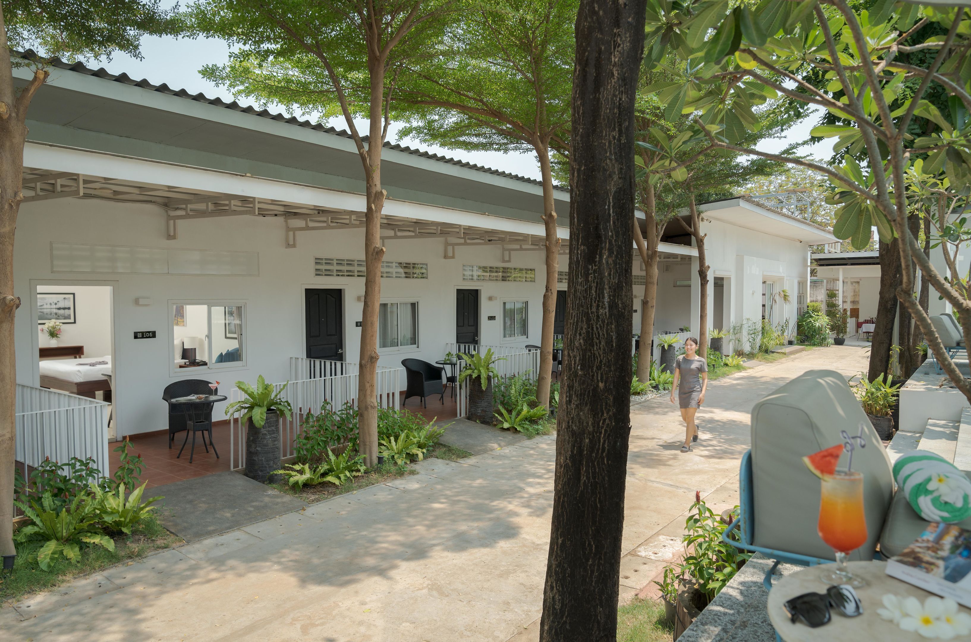 A hotel with a covered outdoor seating area, a pathway, and a person walking.