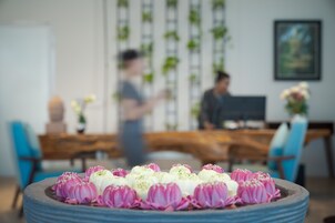 Comedor con una mesa preparada para una comida, un centro de mesa decorativo y un fondo desenfocado con una persona.