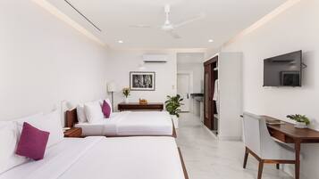 A modern hotel room with two beds, a desk, a chair, a TV, and an air conditioning unit.