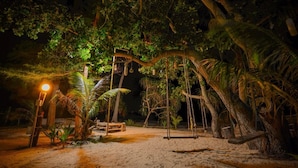 A nighttime outdoor area with a swing set, a wooden bench, and a lamp post. - Baanchaylay Resort (Khanom)