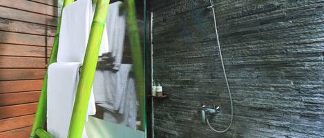 A bathroom with a wooden wall and a shower with a stone-like texture.