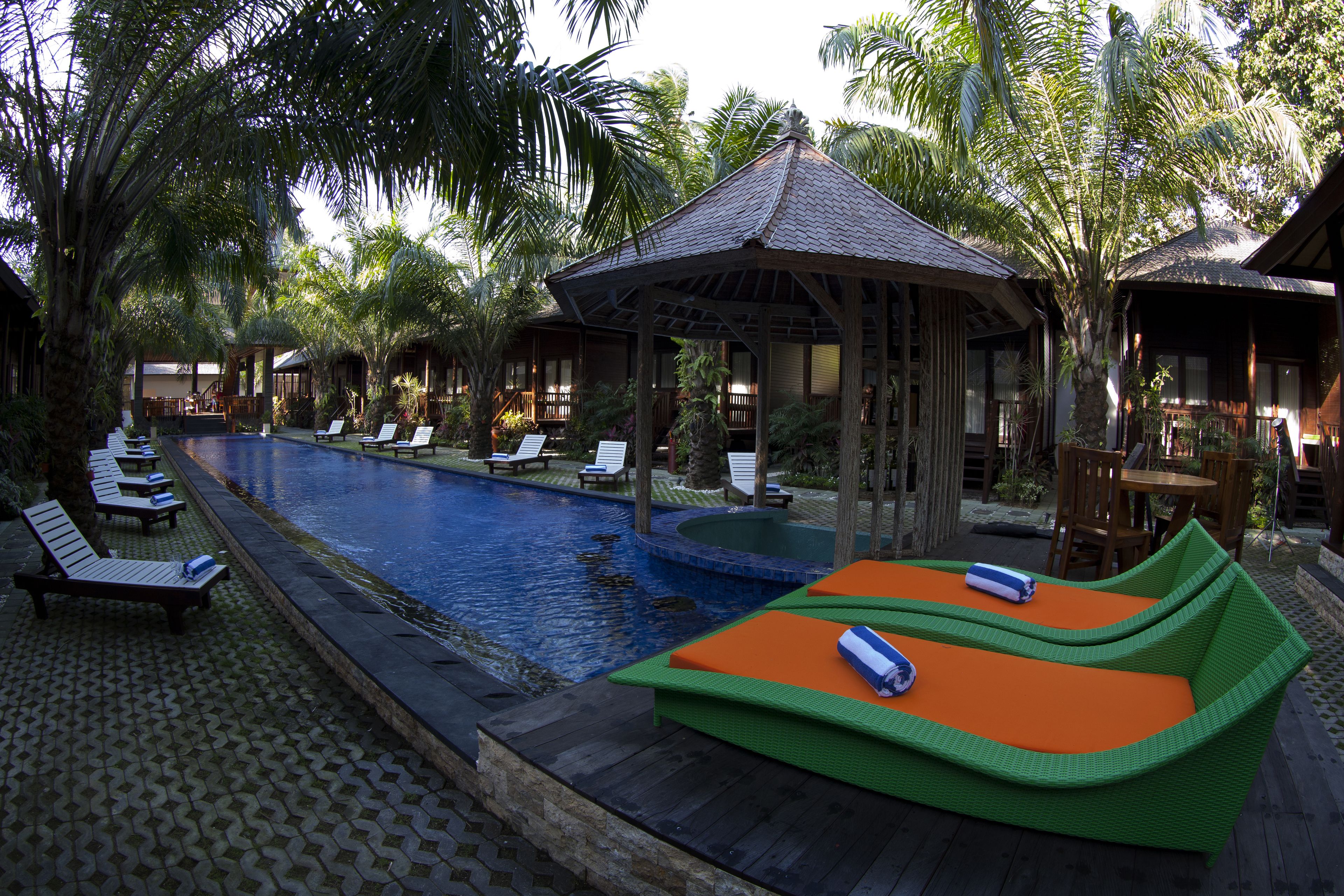 Un espace piscine avec des chaises longues et un petit pavillon.