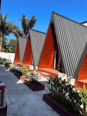 A row of modern, triangular-roofed buildings with a gravel pathway and potted plants.