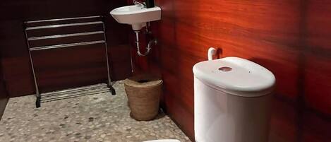 Un baño con inodoro blanco, lavamanos, espejo y toallero.