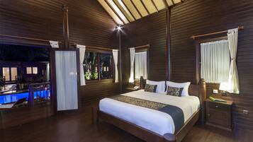 Amplia habitación de madera con una cama, una mesita de noche y un ventanal con cortinas.