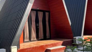 Un edificio moderno con techo triangular, un pequeño espacio de asientos al aire libre y suelo de grava.