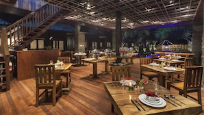 A restaurant with wooden tables and chairs, a bar area, and a staircase.