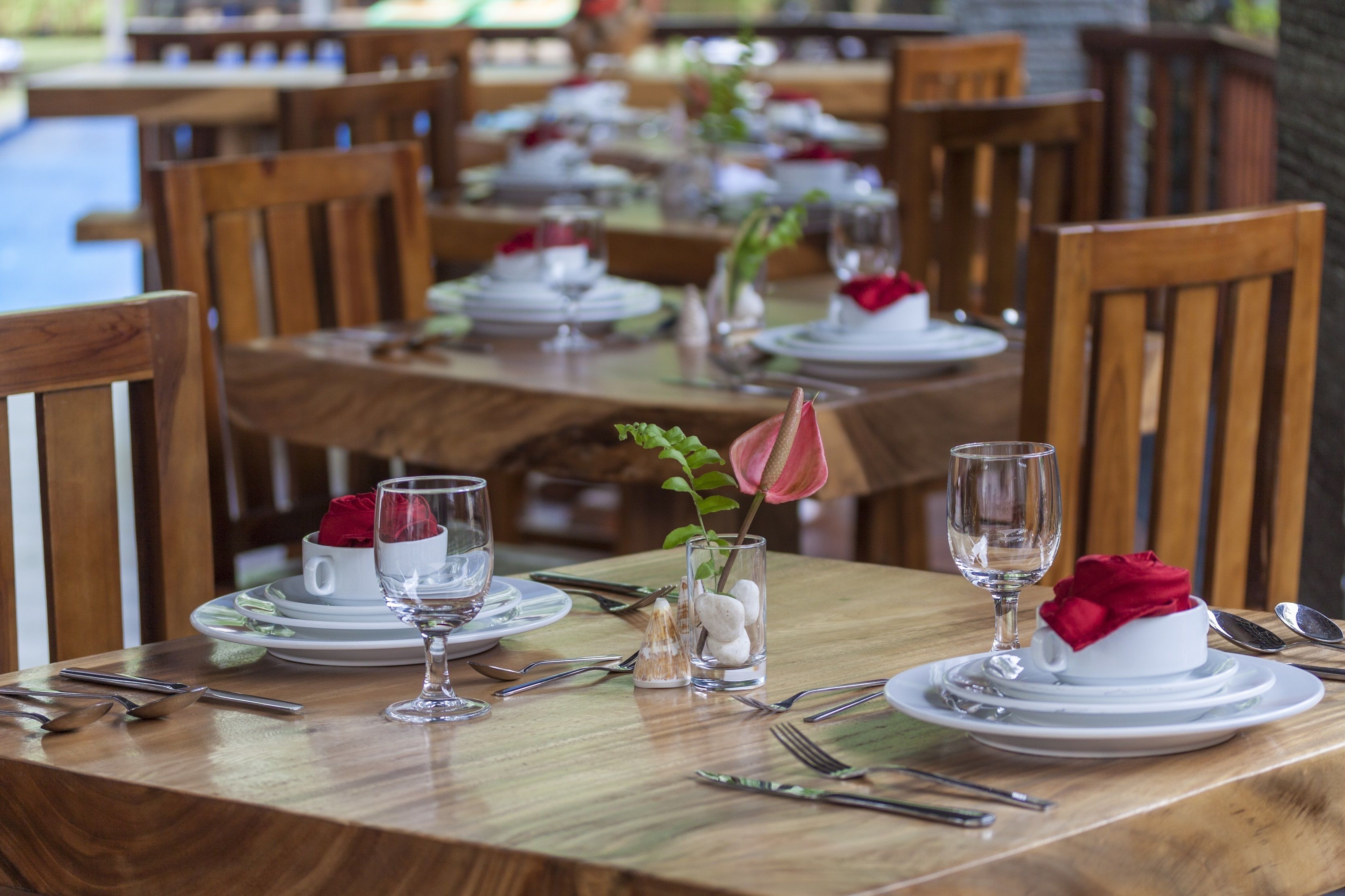A dining table set with white plates, silverware, and a glass of water.